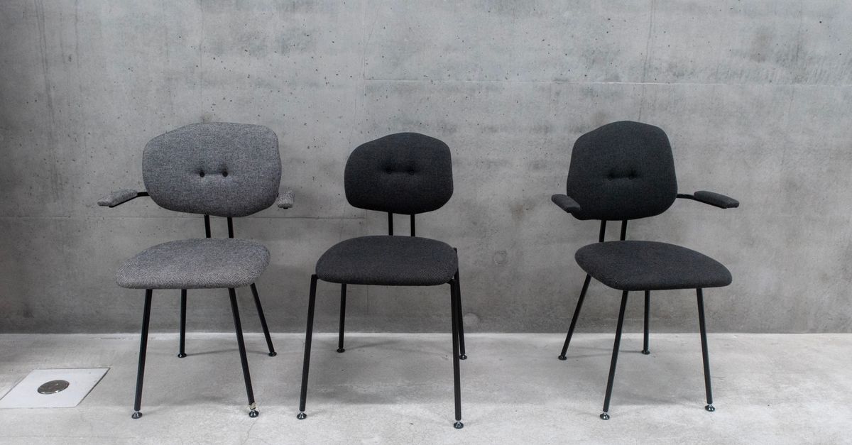 Trois chaises rembourrées aux pieds fins posées contre un mur en béton gris.