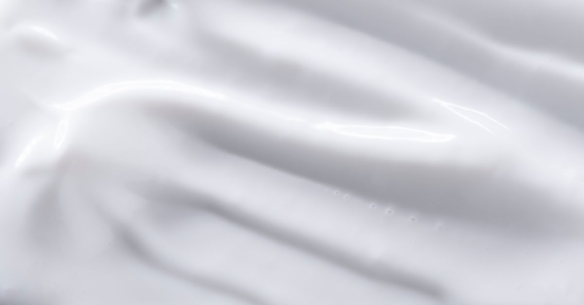 Gros plan sur une texture de sauce blanche lisse et onctueuse aux reflets satinés.