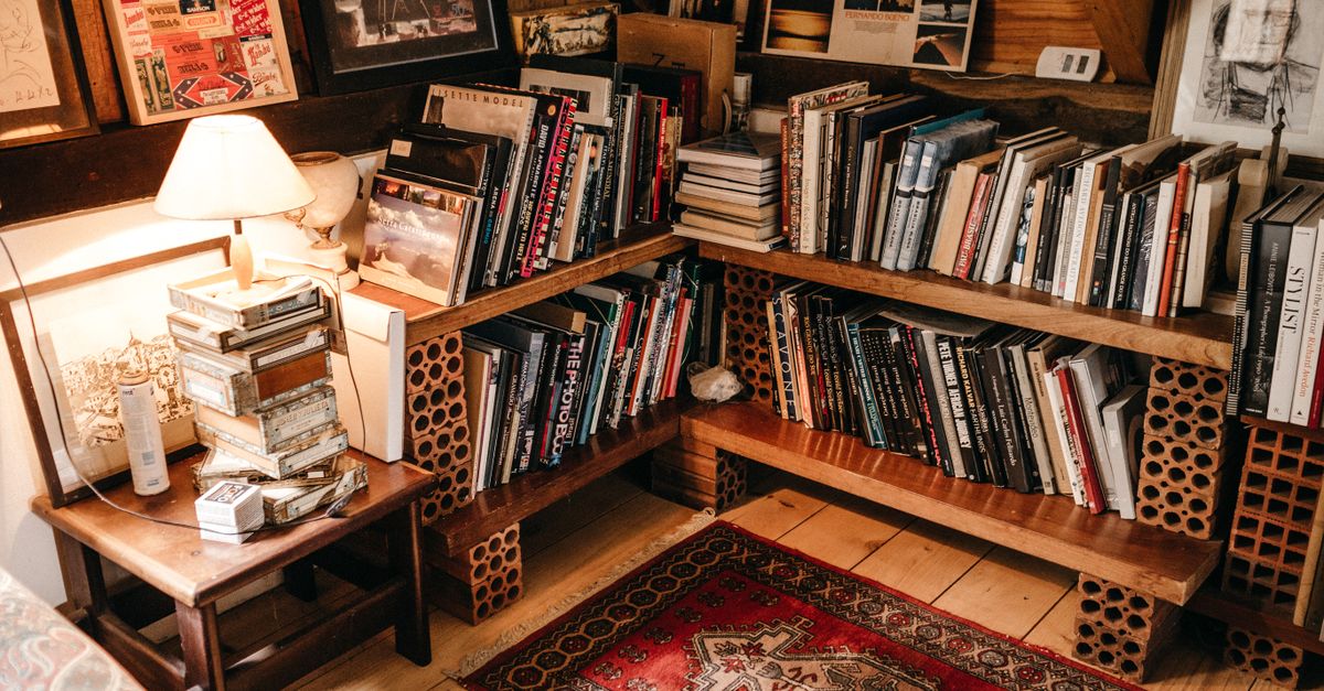 Étagères en bois et briques accueillant des rangées de livres bien organisées dans un coin lecture chaleureux.