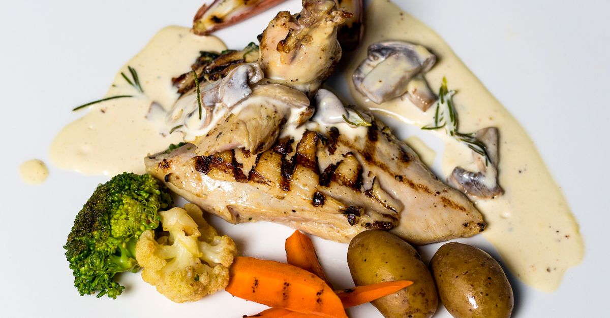 Blanc de poulet grillé nappé de sauce crémeuse aux champignons, servi avec brocoli, chou-fleur, carottes et pommes de terre.