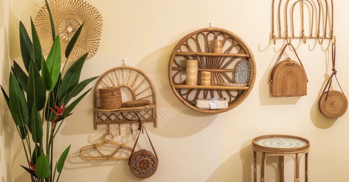 Mur décoré d'étagères en rotin, de crochets suspendus et de petits sacs tressés accrochés au-dessus d'un tabouret.
