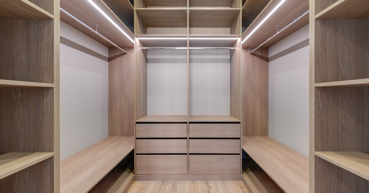 Dressing en bois clair avec étagères, tiroirs et penderies aménagés sous une charpente en pente.