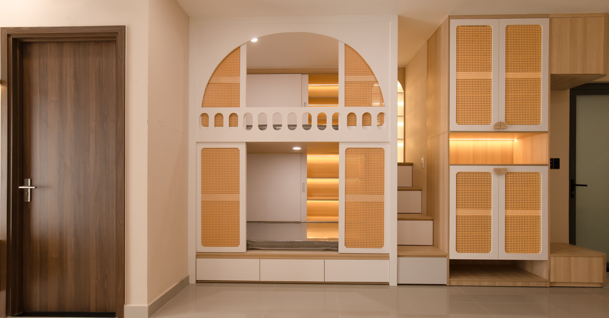 Rangement sur mesure avec tiroirs et niches en bois intégrés sous des marches d'escalier, à côté d'une armoire en cannage clair.