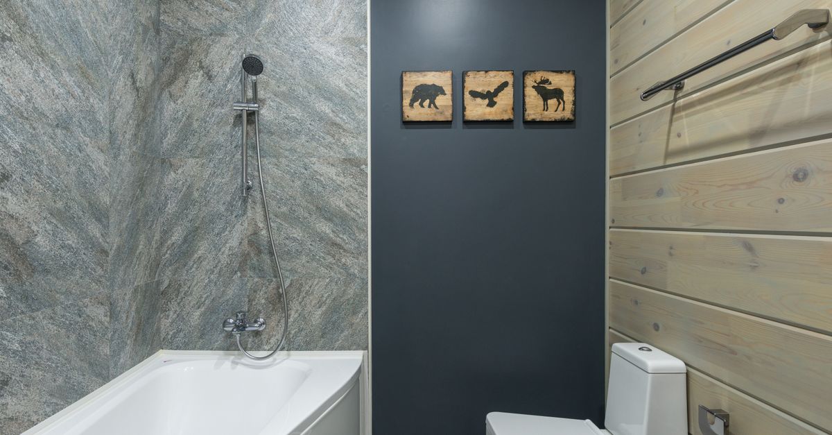 Pommeau de douche chromé brillant fixé au mur dans une salle de bain moderne au-dessus d'une baignoire blanche.