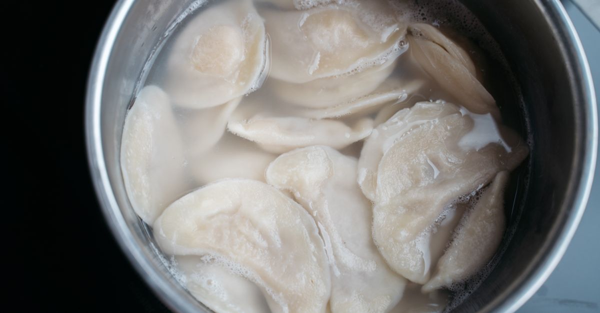Des raviolis farcis en train de cuire dans une casserole d'eau bouillante, vus de dessus.
