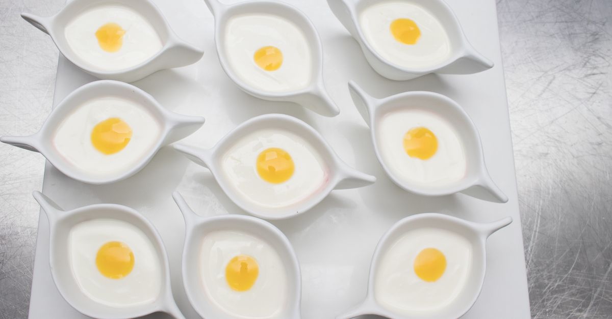 Neuf petits ramequins blancs remplis de blanc d'œuf opaque avec un jaune d'œuf coulant au centre, vus de dessus.