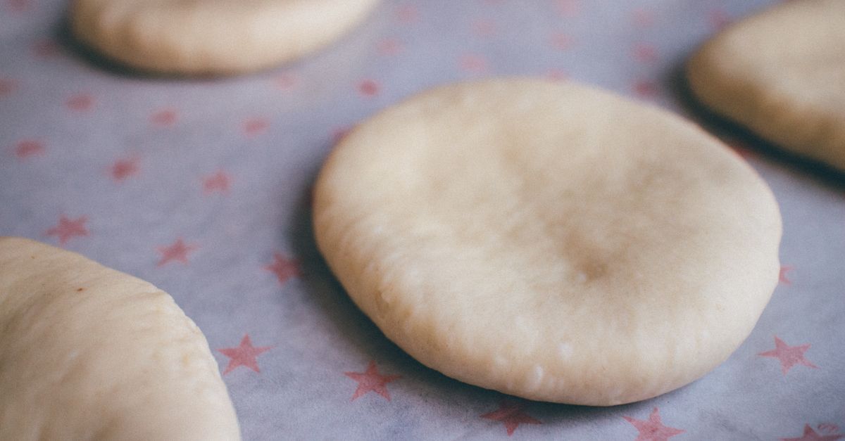Des galettes rondes de pâte posées côte à côte sur un papier décoré d'étoiles roses, prêtes à être congelées.