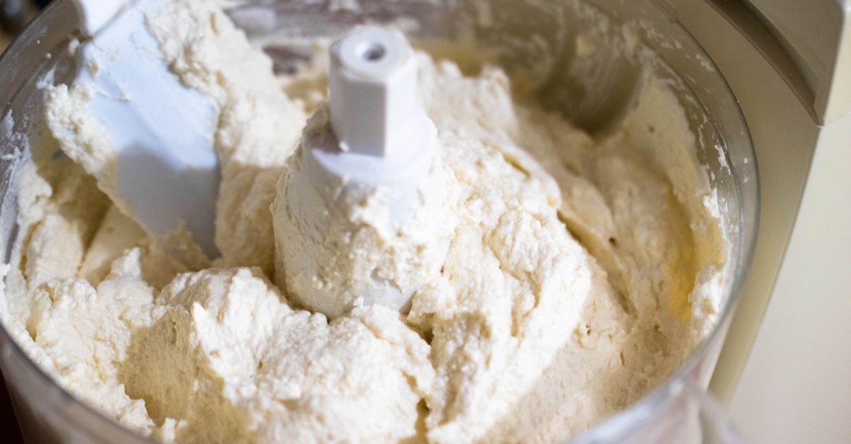 Du fromage frais type ricotta à la texture crémeuse dans un robot culinaire, prêt à être transféré dans un contenant.