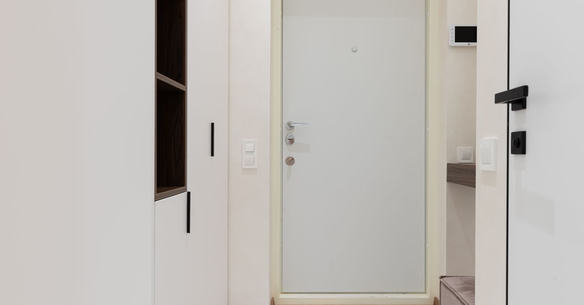 Entrée d'appartement avec une porte d'entrée blanche encadrée de meubles de rangement muraux intégrés des deux côtés.