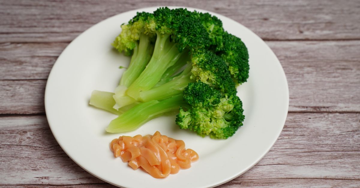 Des fleurettes de brocoli vert vif cuites à la vapeur disposées sur une assiette blanche à côté d'une portion de saumon fumé.