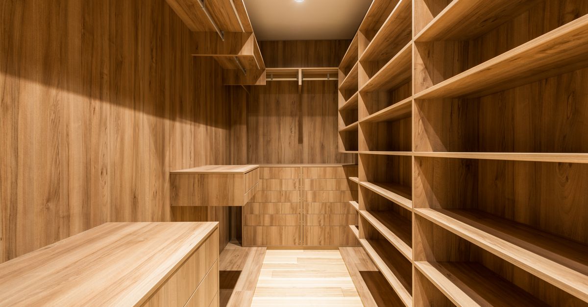 Dressing en bois avec étagères vides et penderie, éclairé par un plafonnier, sans traces d'humidité