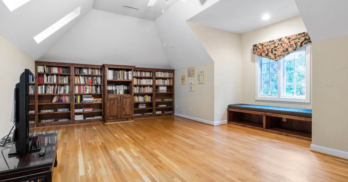 Grenier aménagé avec des bibliothèques en bois sur mesure installées sous le plafond en pente, le long des murs bas de la pièce mansardée.