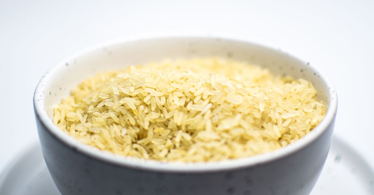 Un bol de riz cuit aux grains jaunes bien détachés, vu en gros plan.