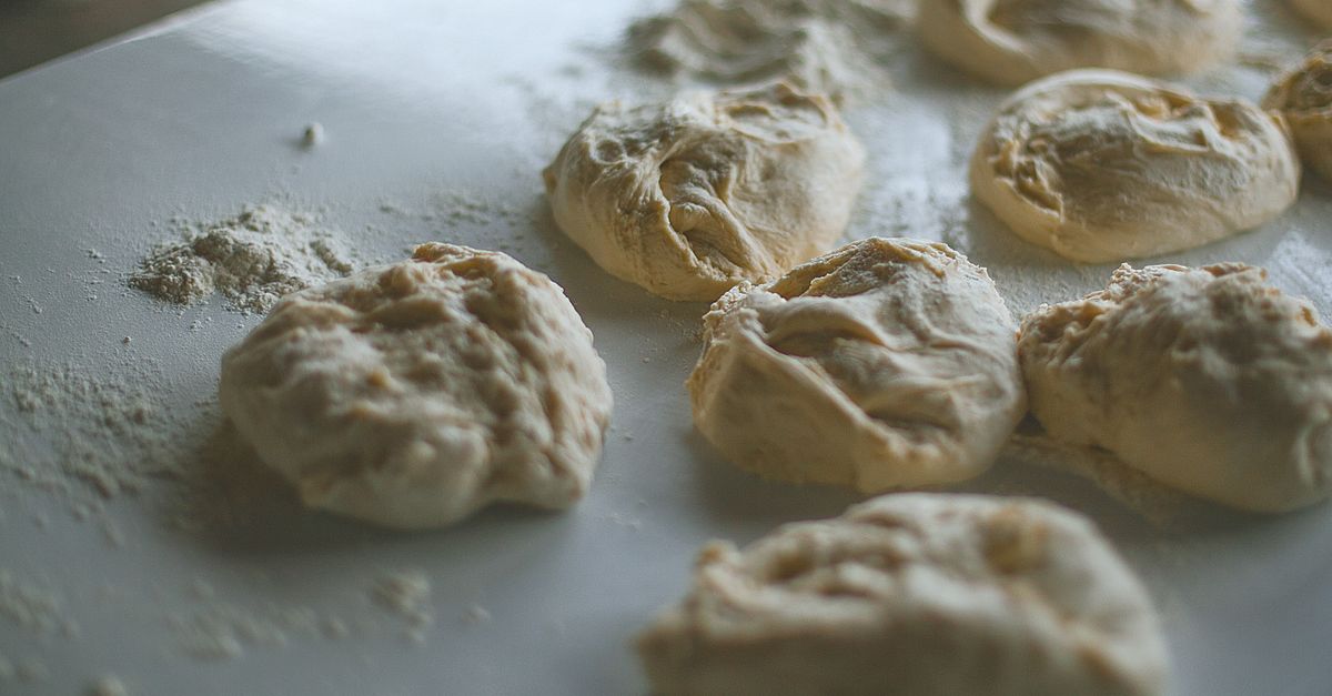 Des portions de pâte levée façonnées en boules disposées sur un plan de travail fariné.
